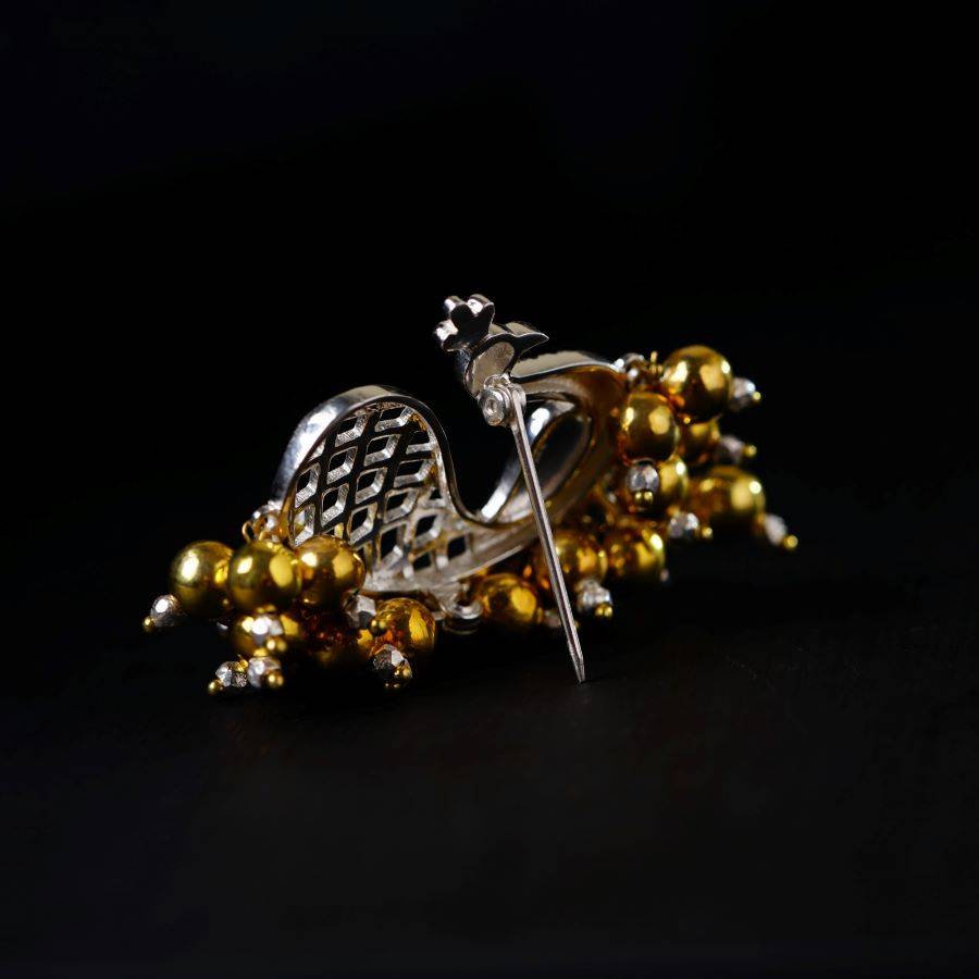 a brooch with beads and a bird on it