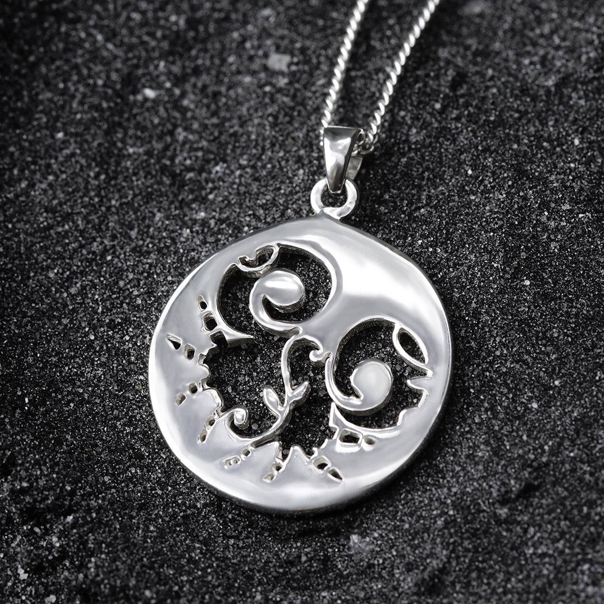 a silver pendant with a design on it