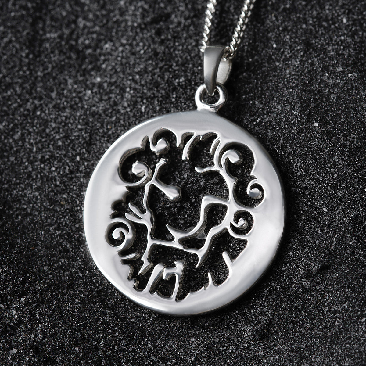 a silver pendant with a design on it