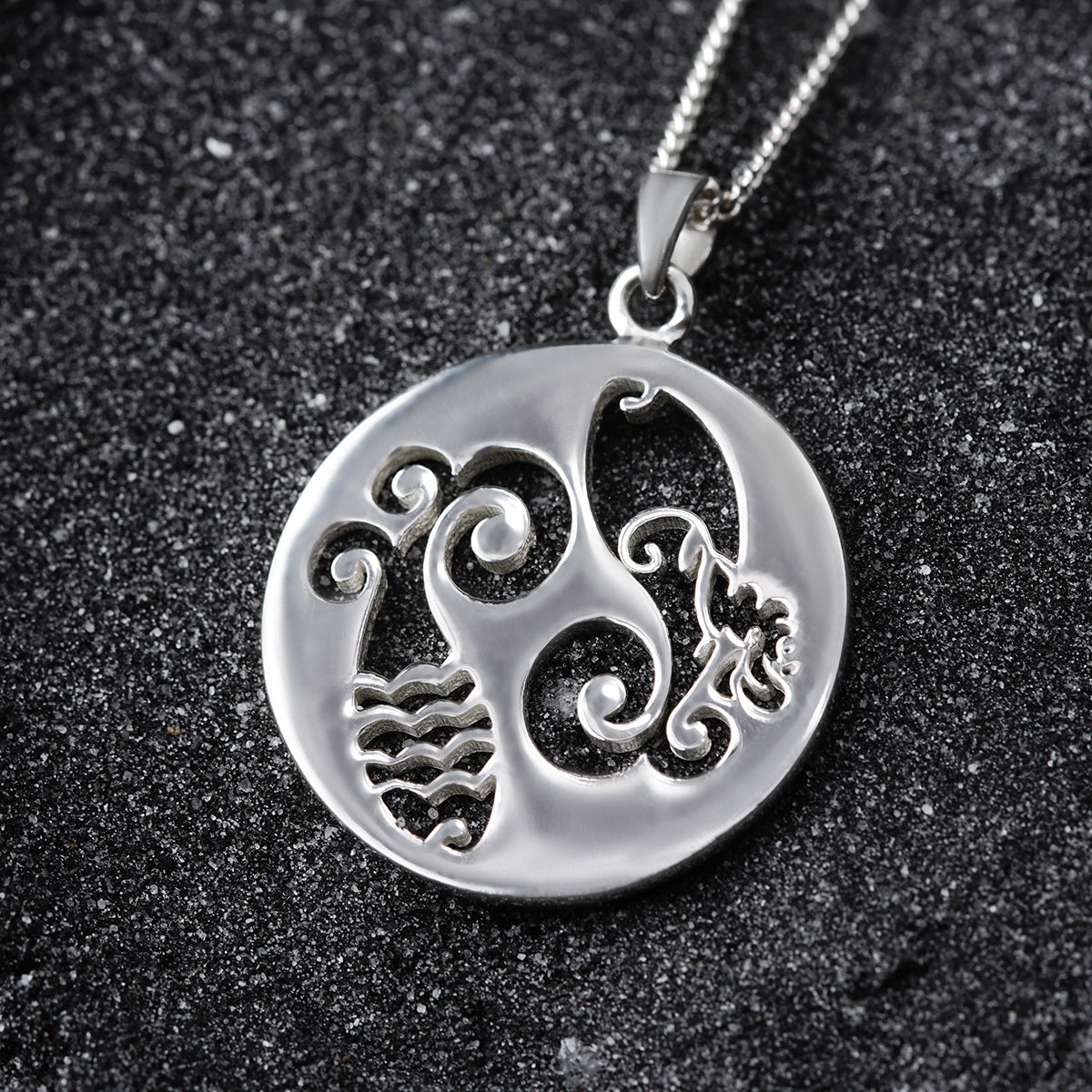a silver pendant with a design on it