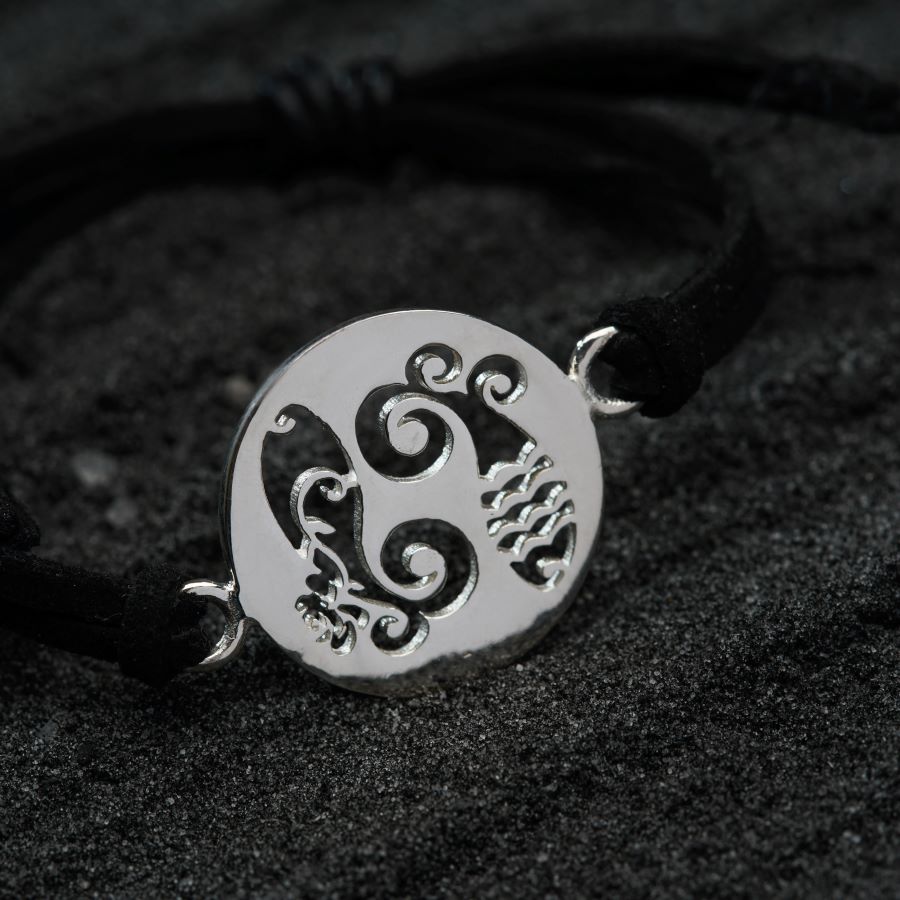 a black cord bracelet with a silver pendant on it