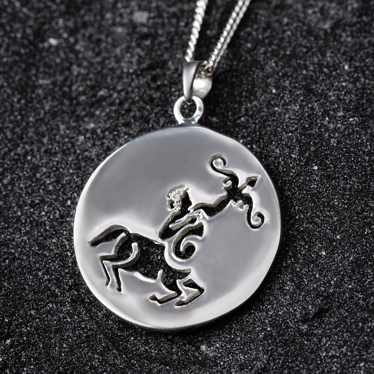 a silver pendant with a horse on it