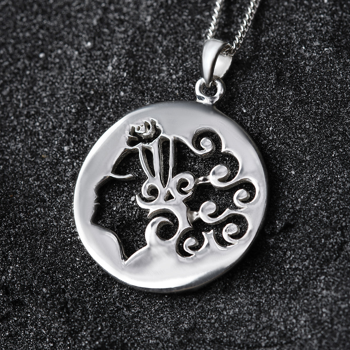 a silver pendant with a design on it