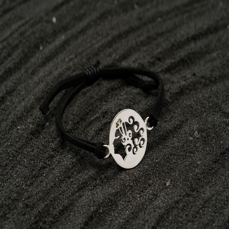 a black cord bracelet with a silver plate on top of it