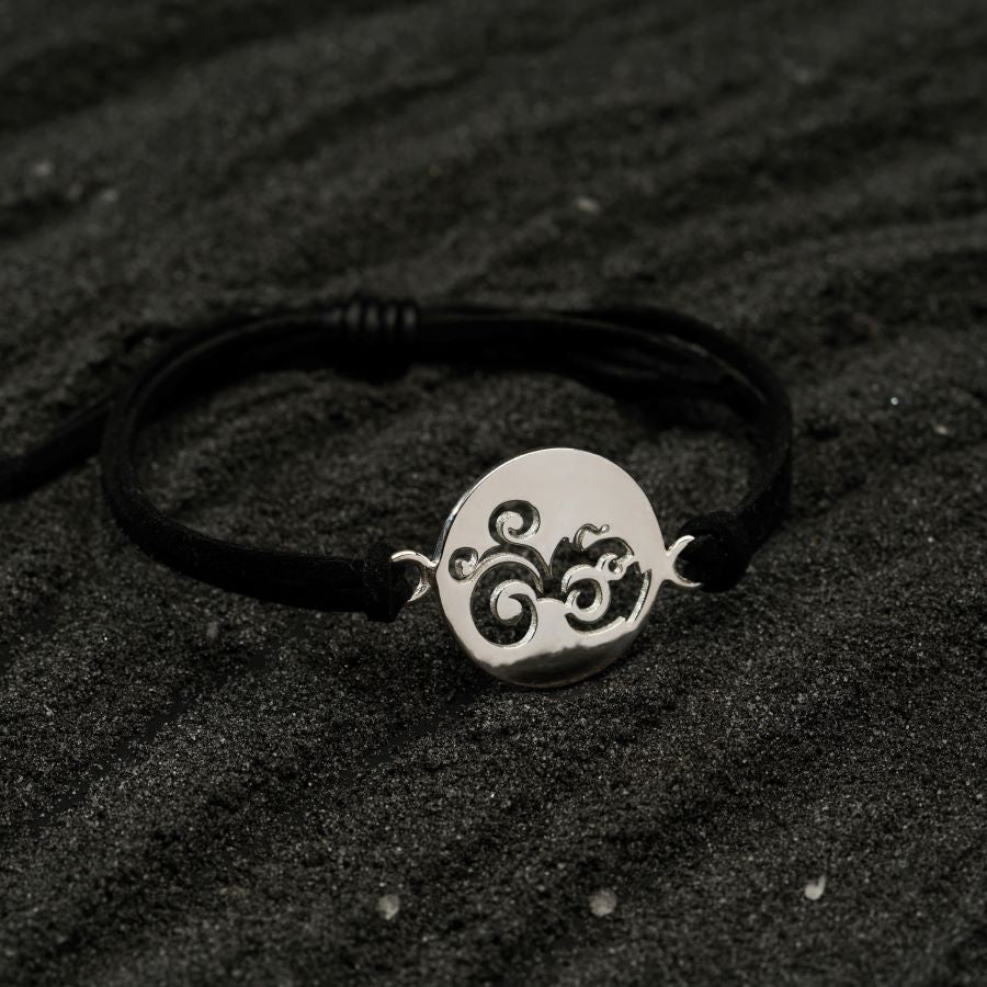 a black cord bracelet with a silver plate on top of it