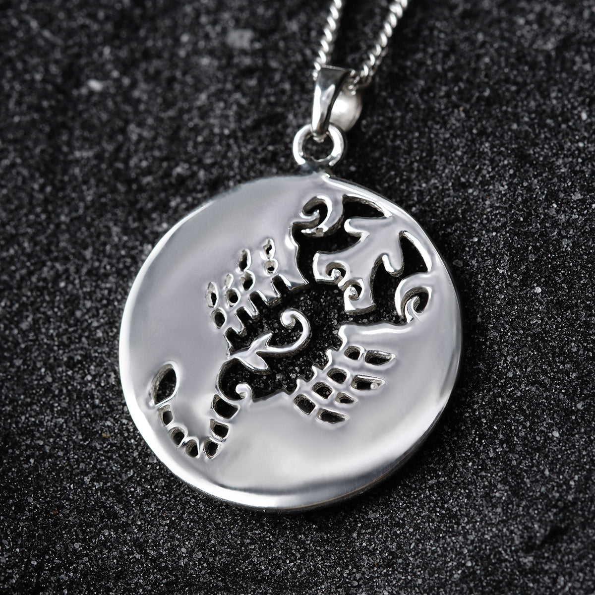 a silver pendant with a dragon on it