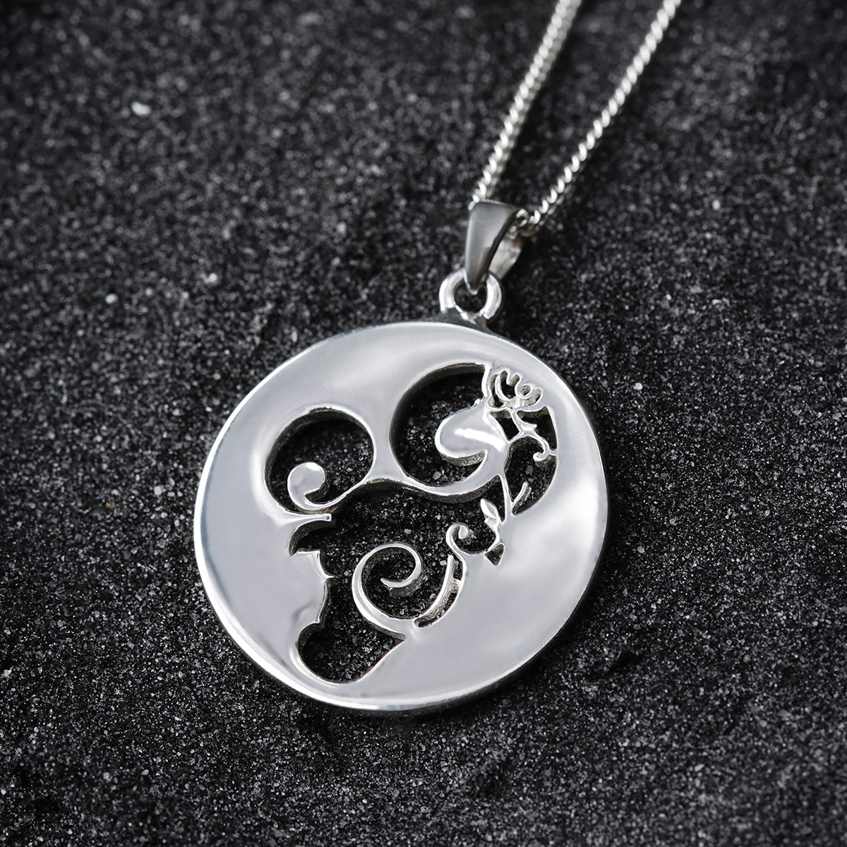 a silver pendant with a design on it