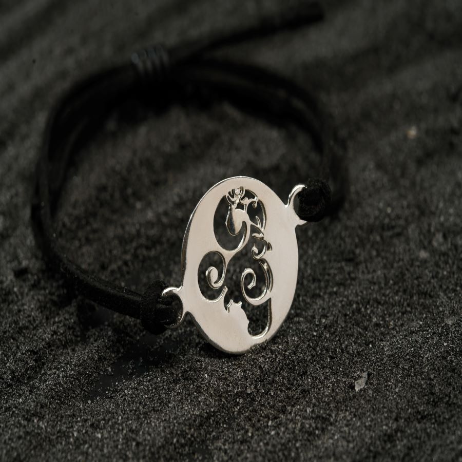 a bracelet with a silver pendant on a black cord