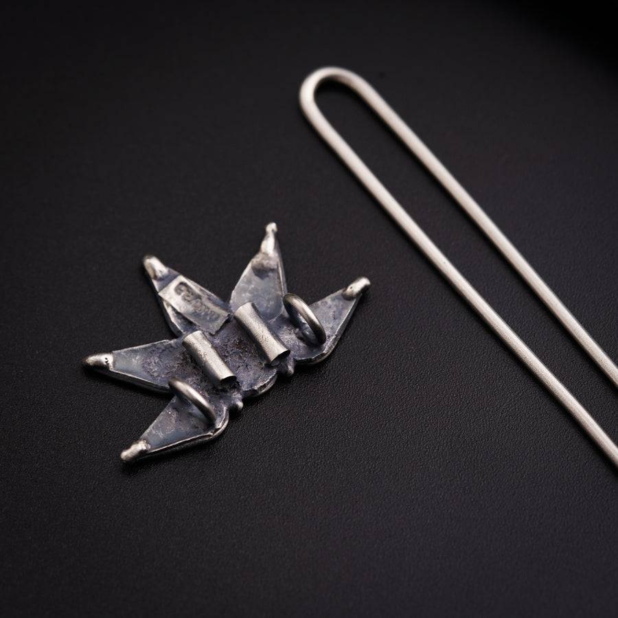 a pair of scissors and a pin on a black surface