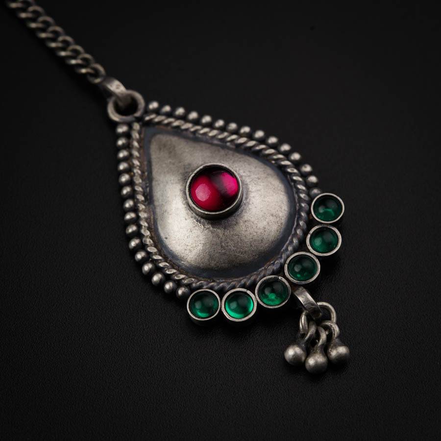 a silver pendant with a red and green stone