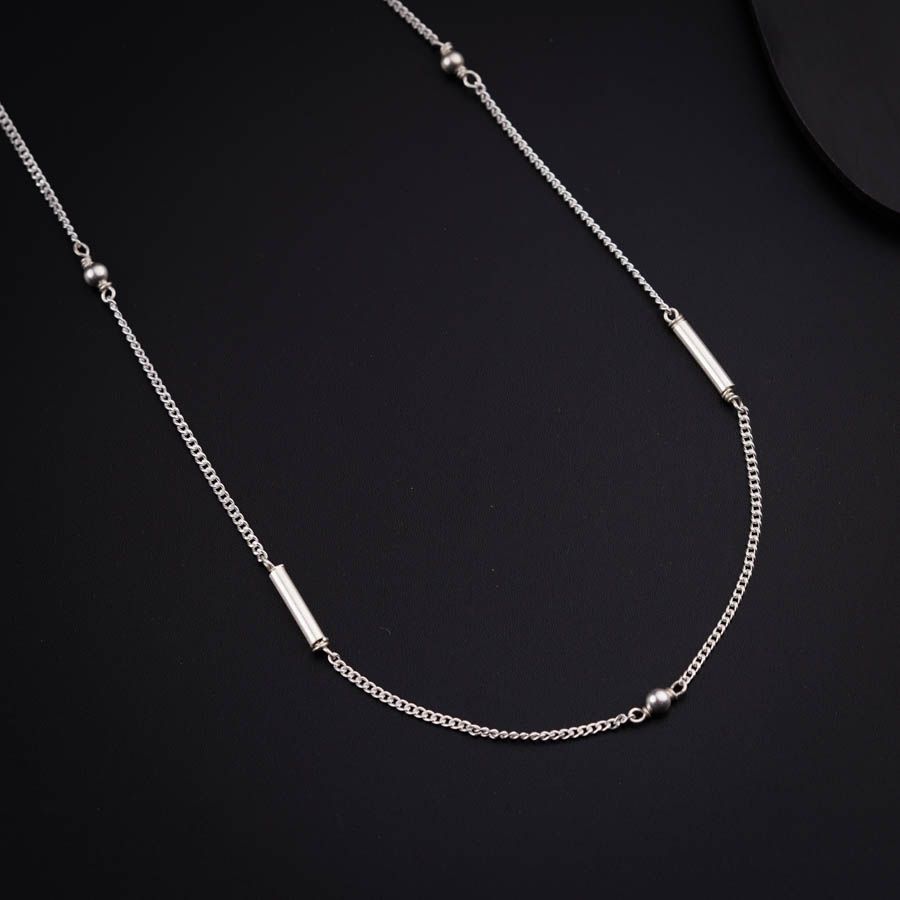 a silver necklace on a black surface