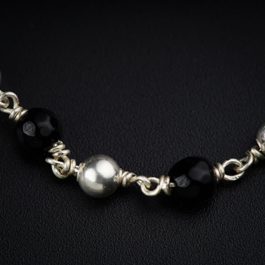 a black and silver beaded necklace on a black surface