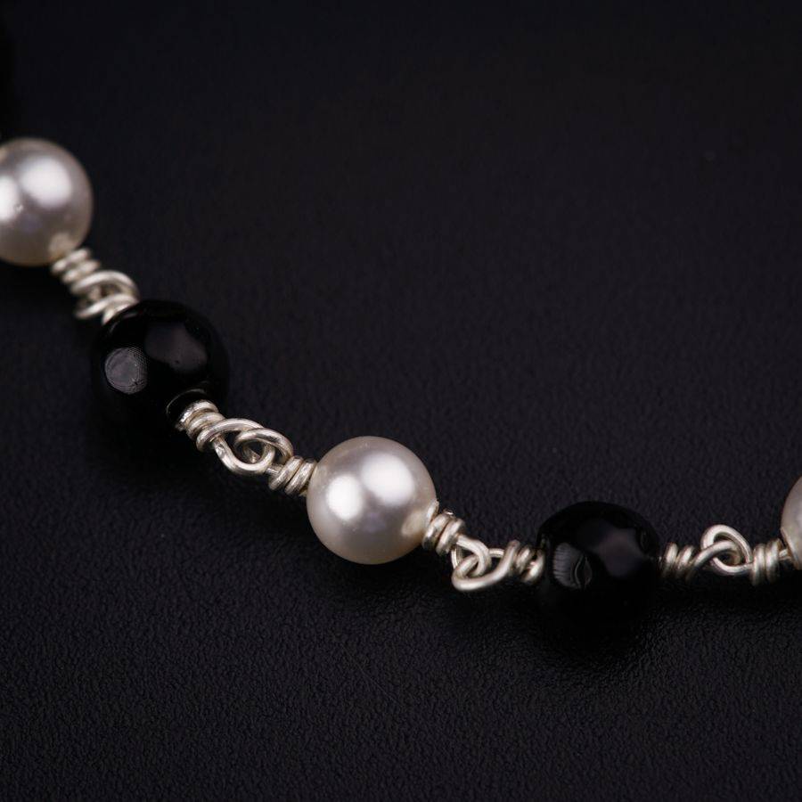 a black and white beaded necklace on a black surface