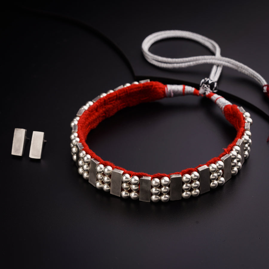 a red bracelet with silver beads on a black surface