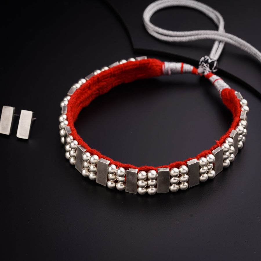 a red string bracelet with silver beads on a black surface