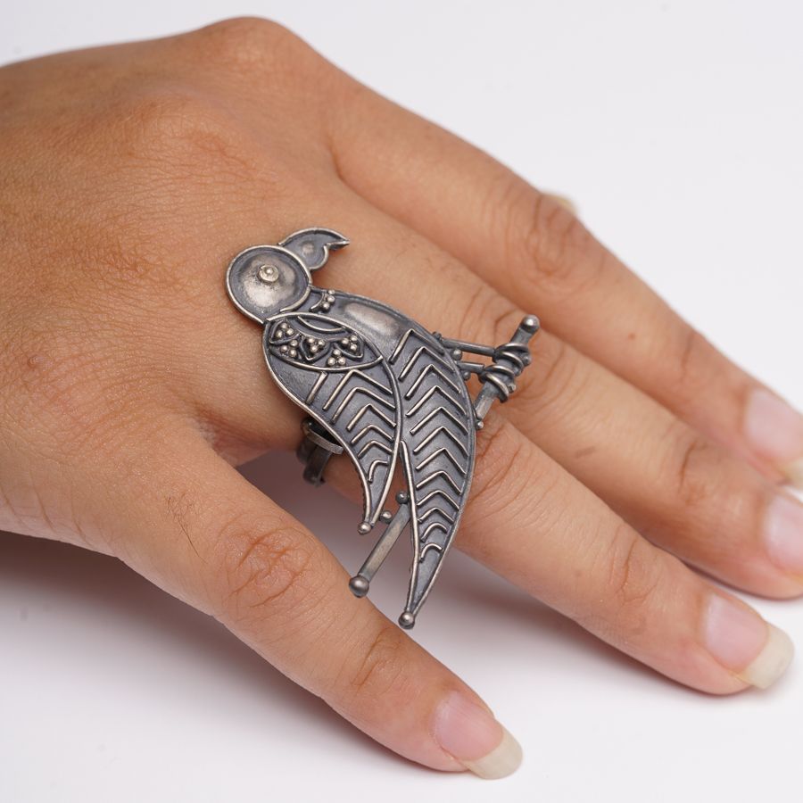 a woman's hand wearing a ring with a bird on it