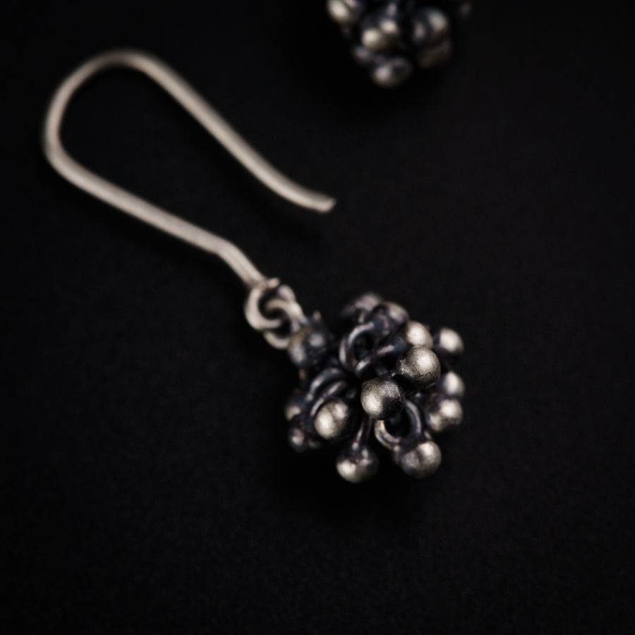 a pair of silver earrings on a black background