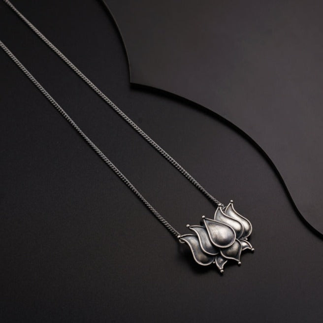 two silver necklaces on a black surface