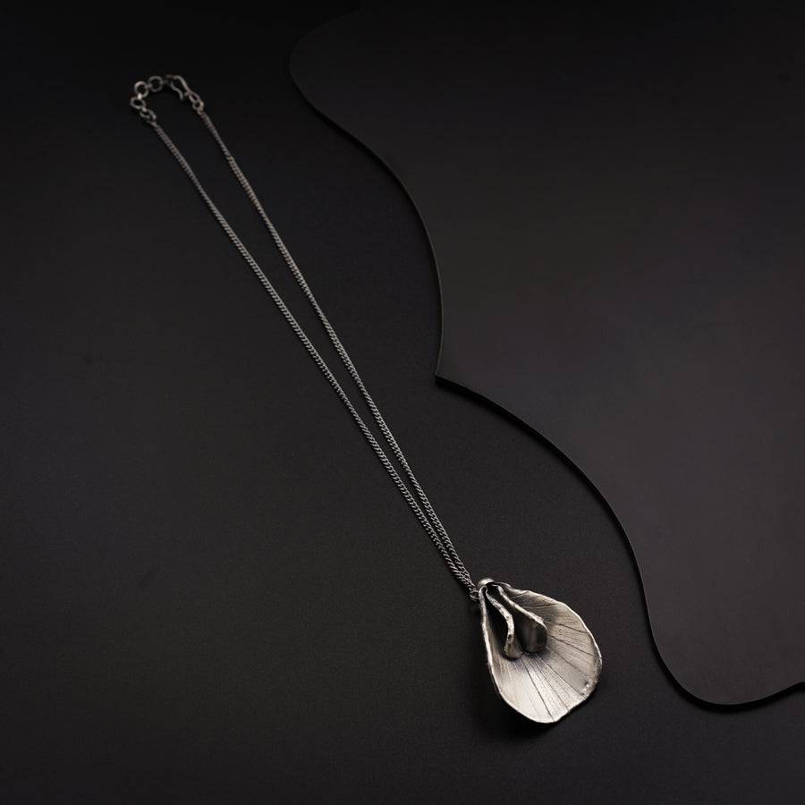 a silver necklace with a leaf on it