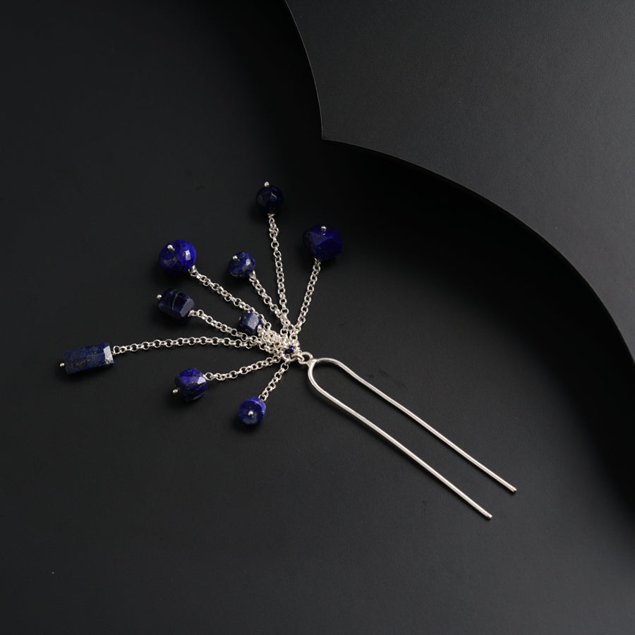 a hair pin with blue beads on a black background