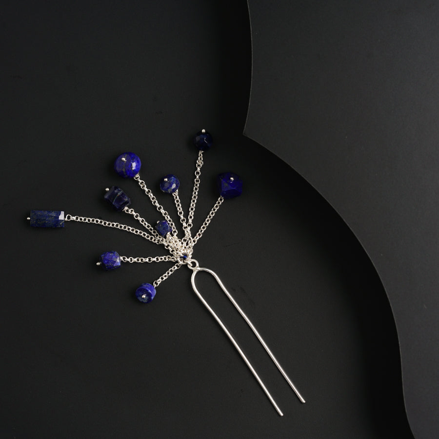 a hair pin with blue beads on a black background