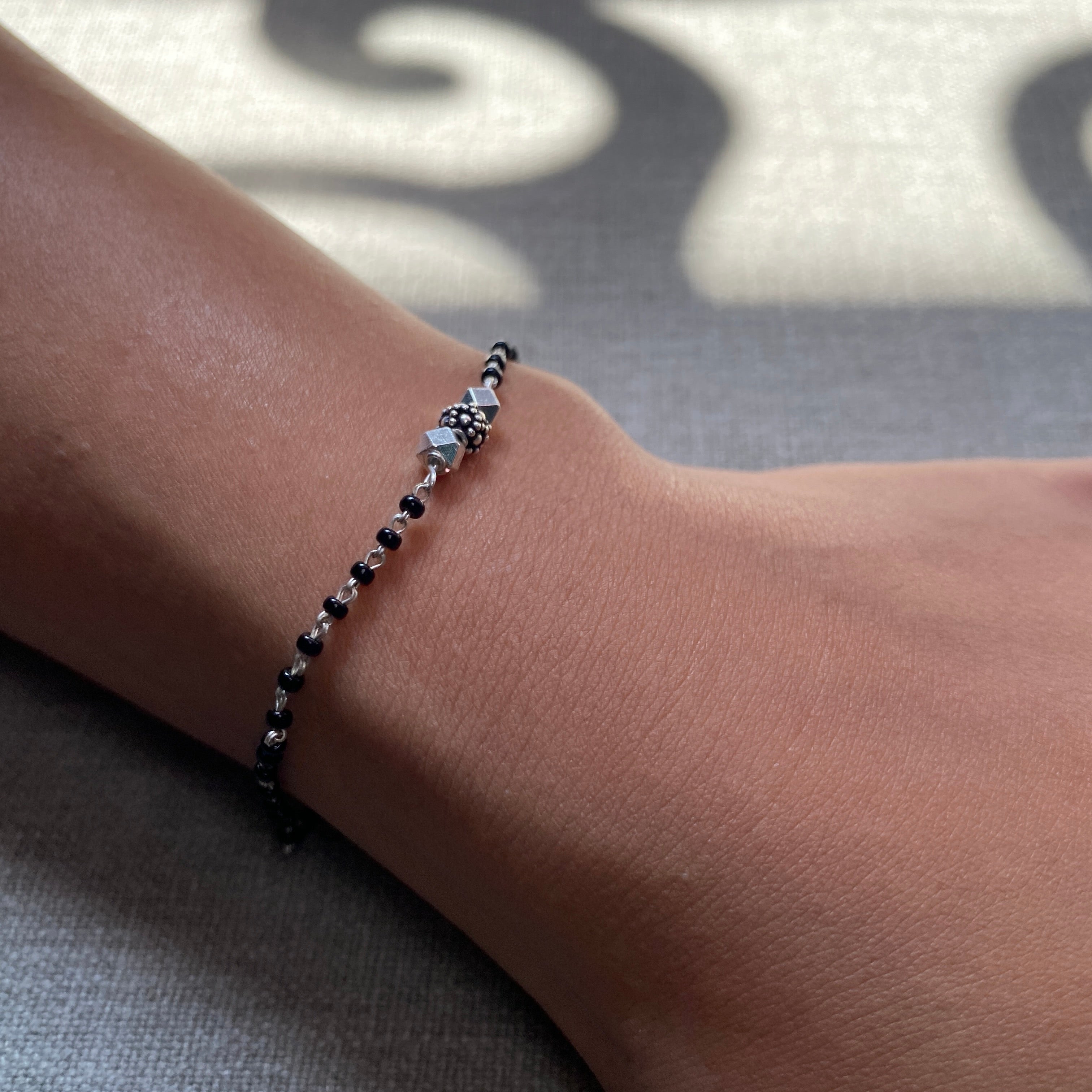 a woman's arm wearing a black beaded bracelet