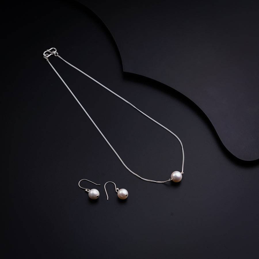 a necklace and earrings on a black surface