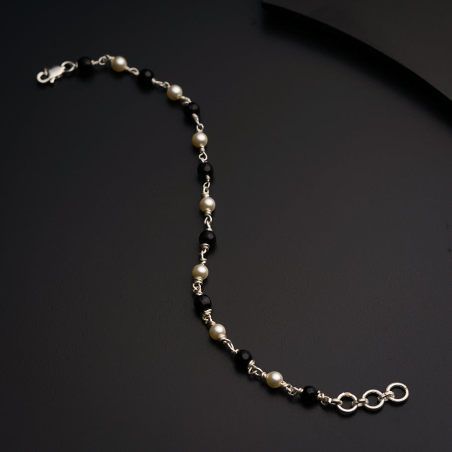 a black and white beaded necklace on a black surface