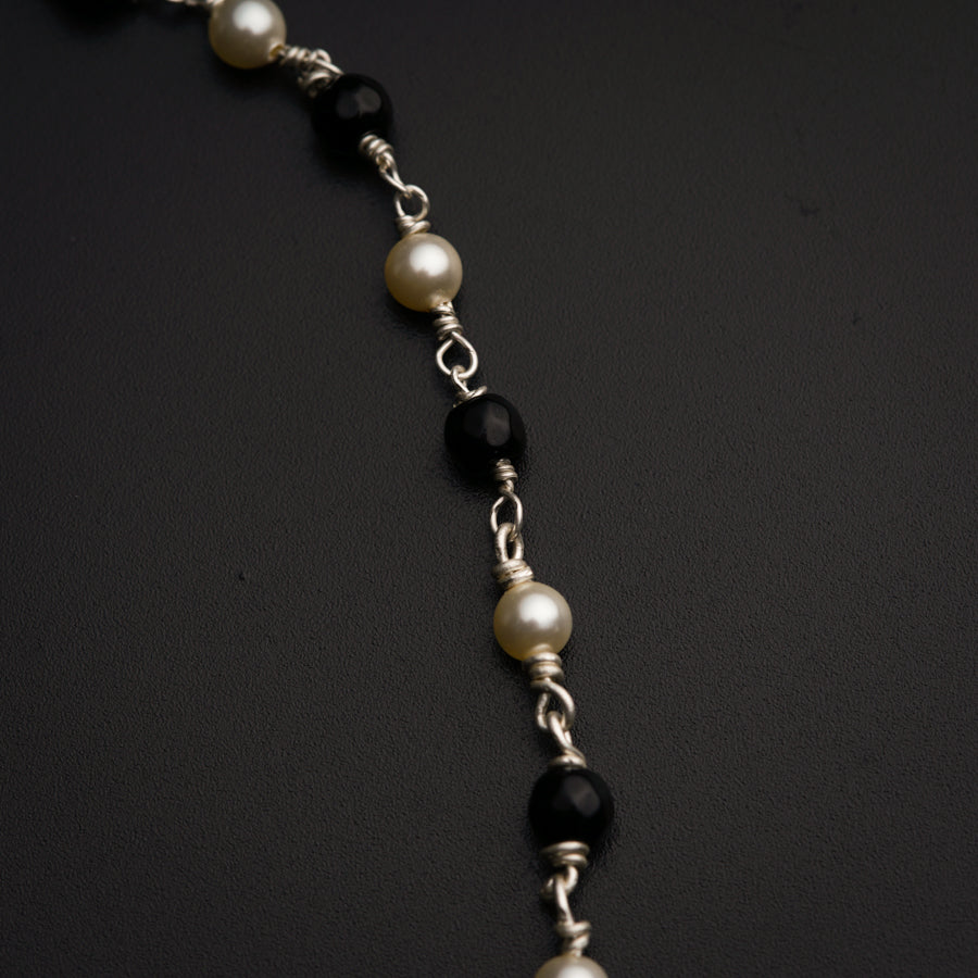 a black and white beaded necklace on a black surface