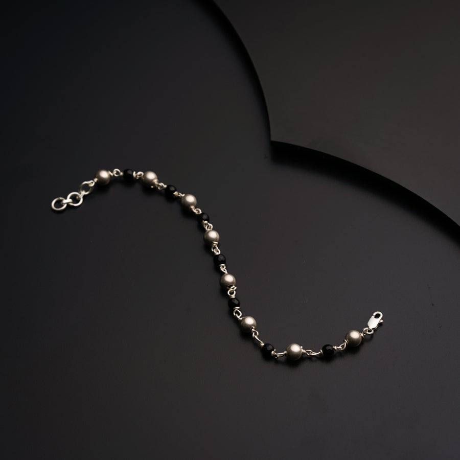 a silver beaded necklace on a black surface