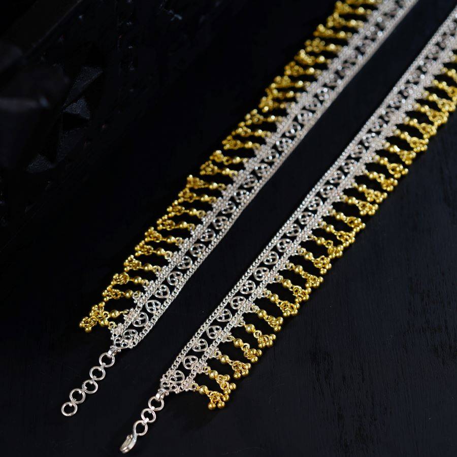 two gold and silver chains on a black surface