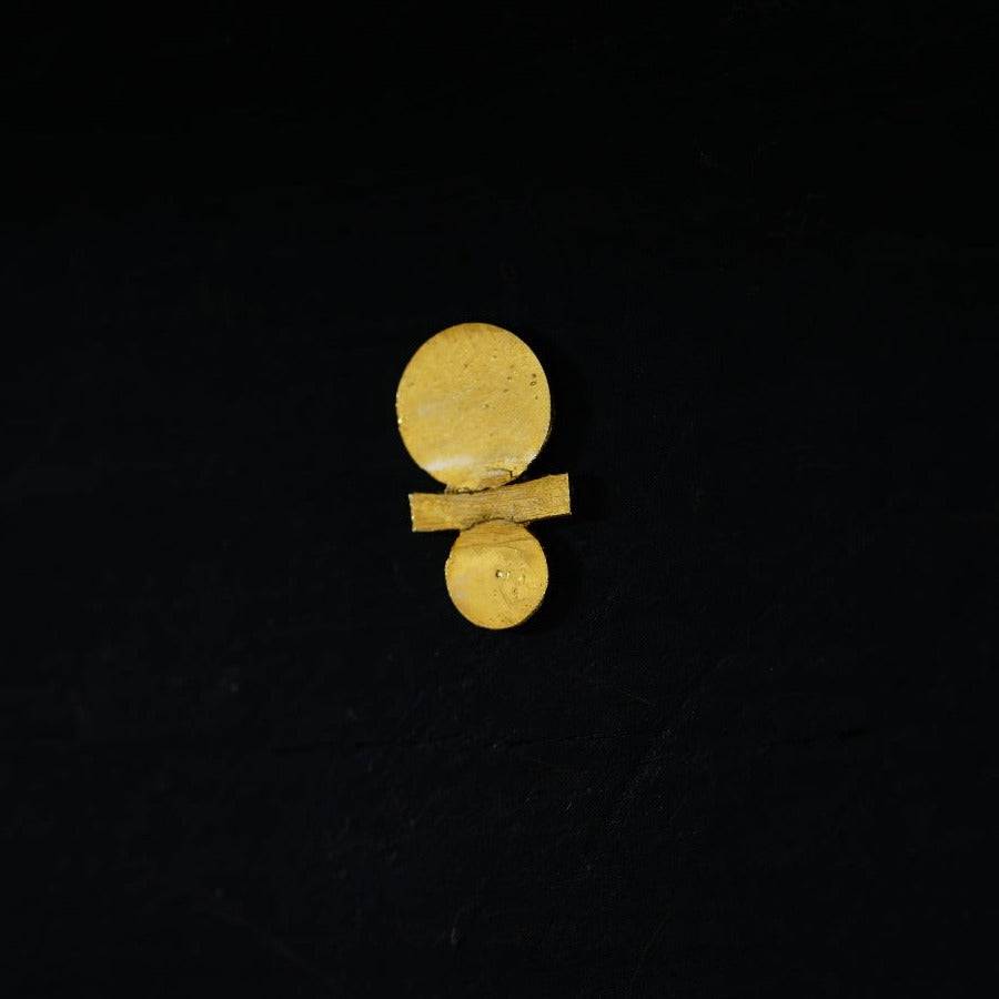 a pair of gold earrings sitting on top of a black surface