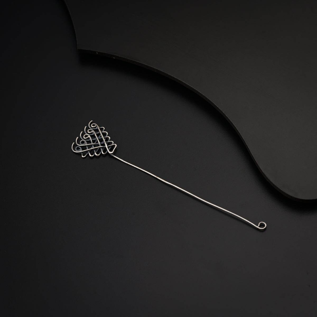 a metal hair comb on a black surface