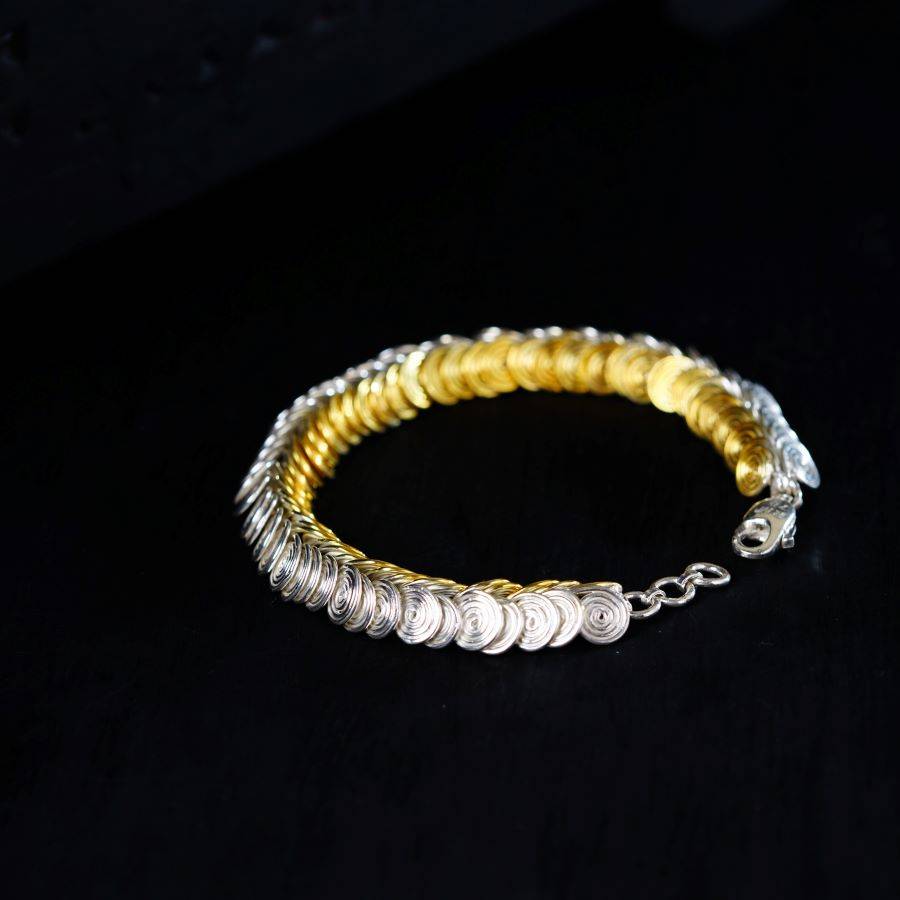 a silver and gold bracelet on a black background