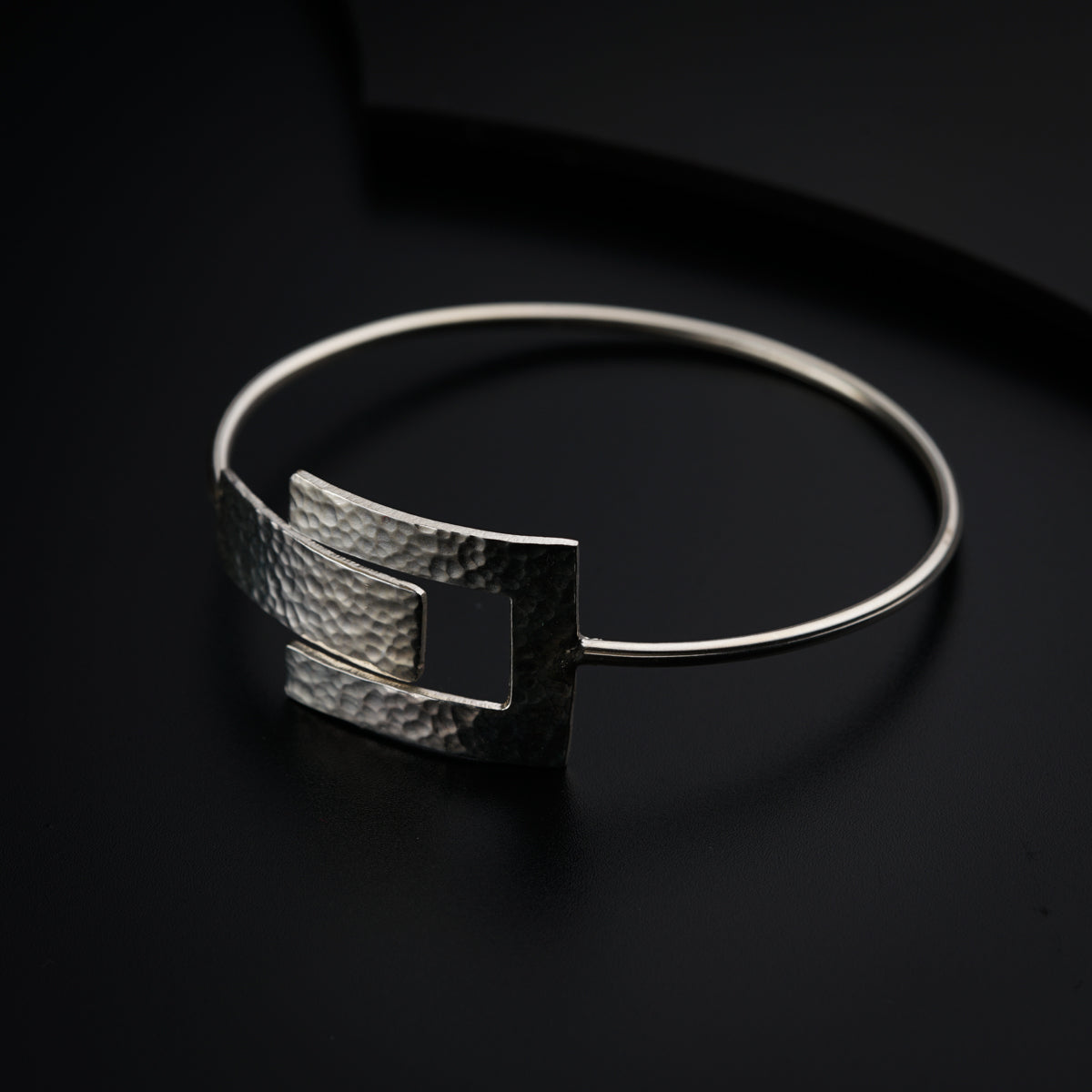 a close up of a silver bracelet on a black surface