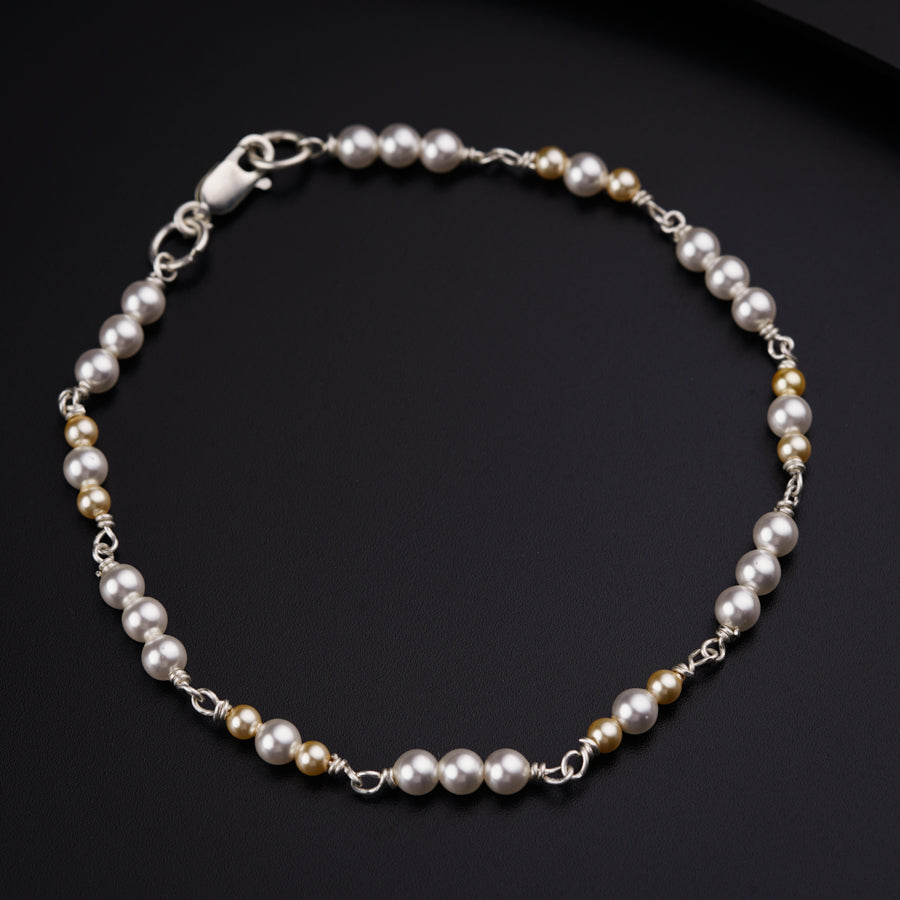 a bracelet with pearls and silver beads on a black surface
