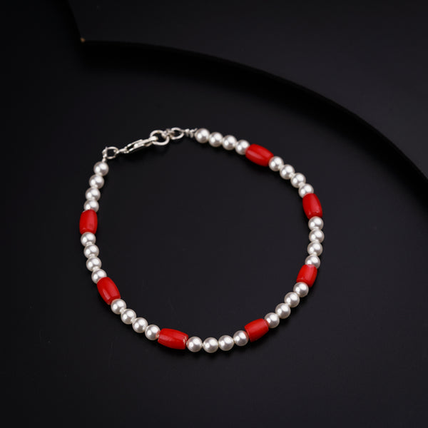 a red and silver beaded bracelet on a black surface
