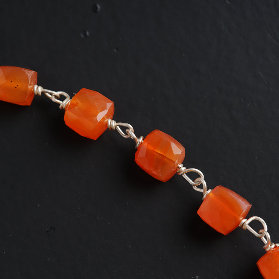 a bracelet with orange glass beads on a black surface