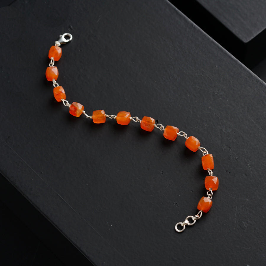 an orange beaded bracelet on a black surface