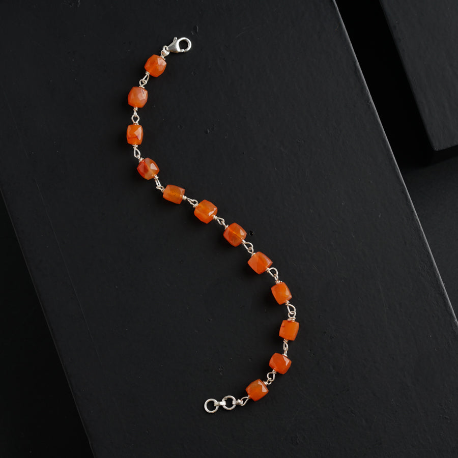 a bracelet with orange beads on a black surface