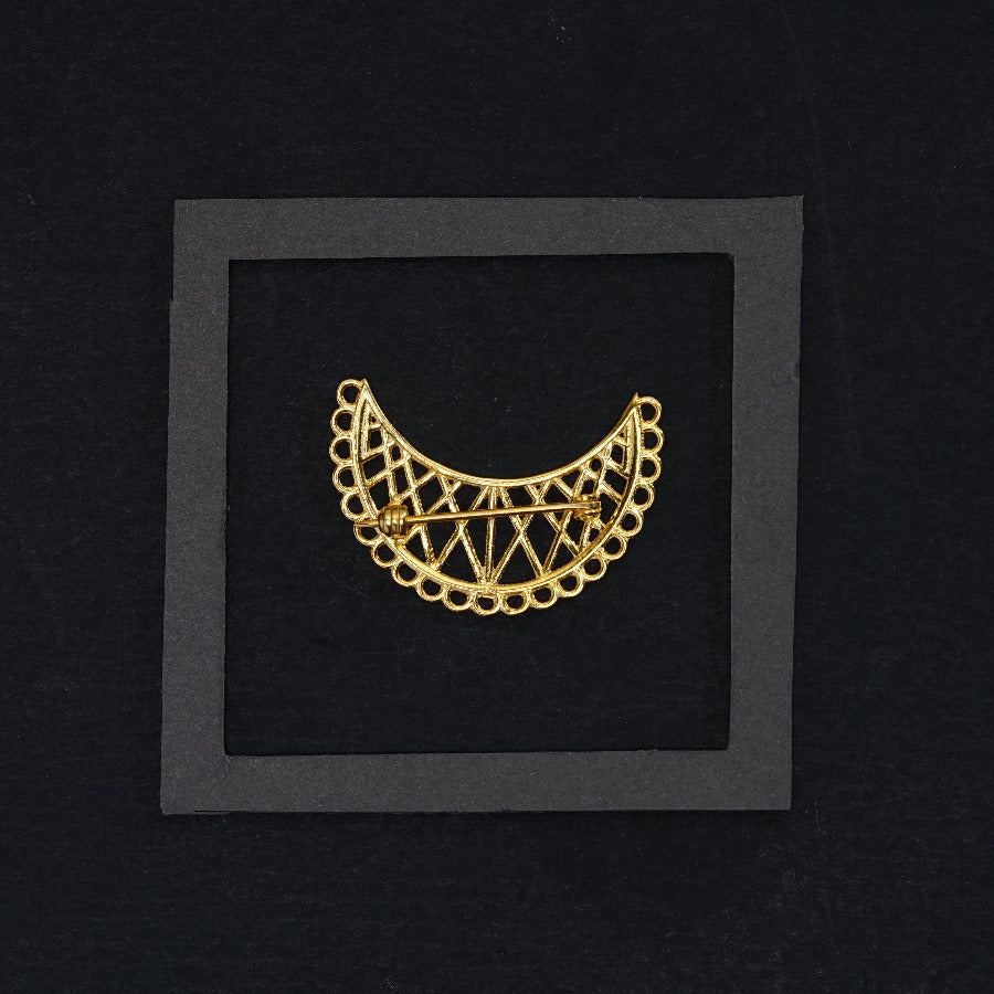 a gold brooch in a black frame