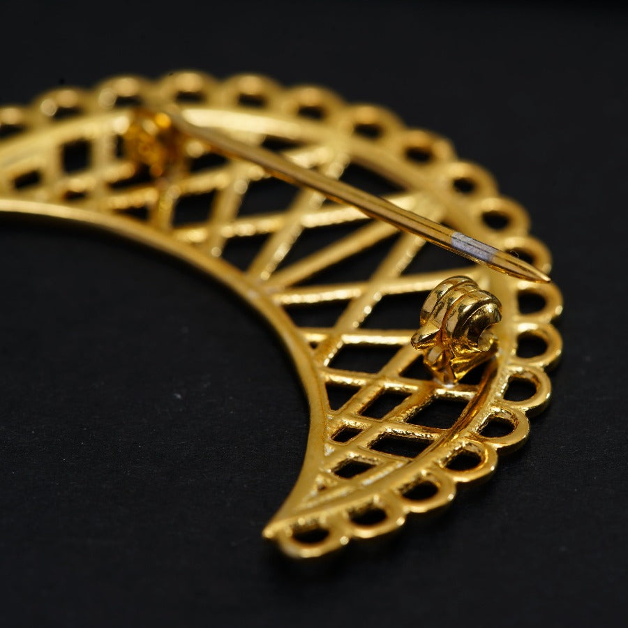 a close up of a gold brooch on a black surface