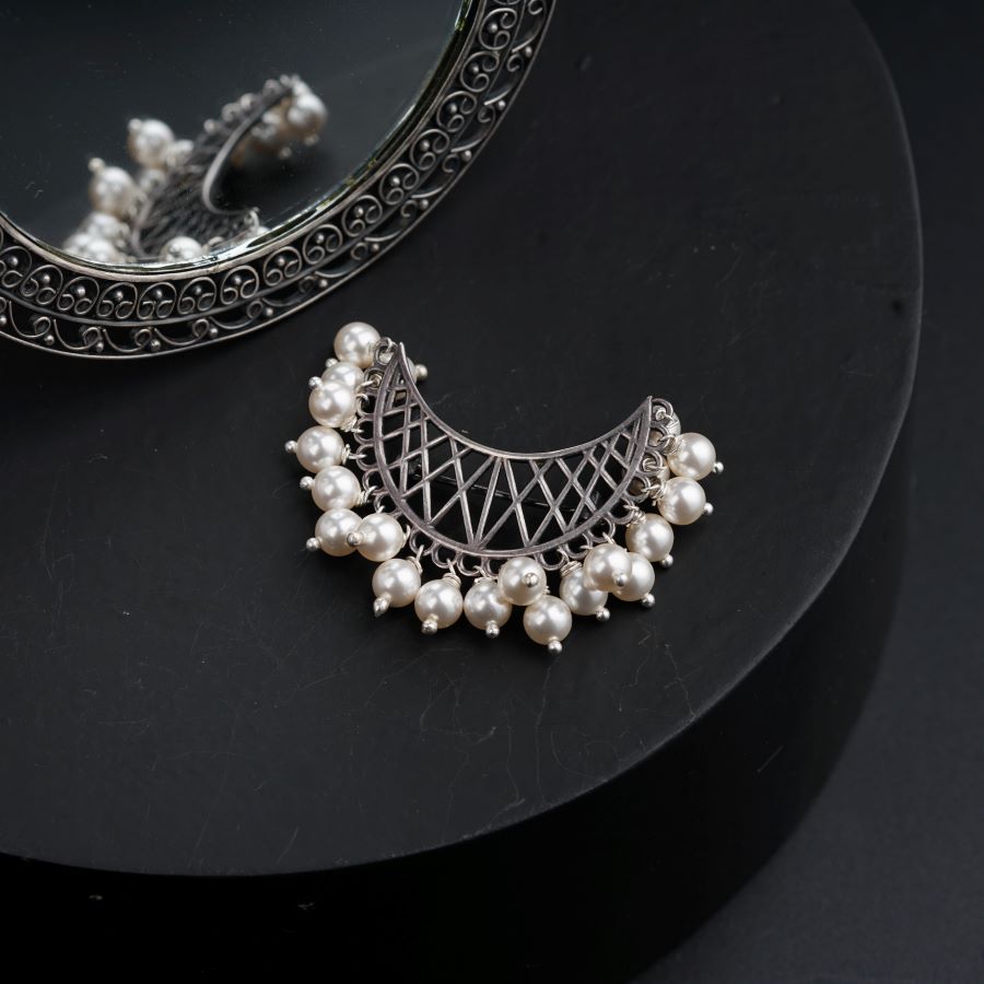 a close up of a brooch with a mirror in the background