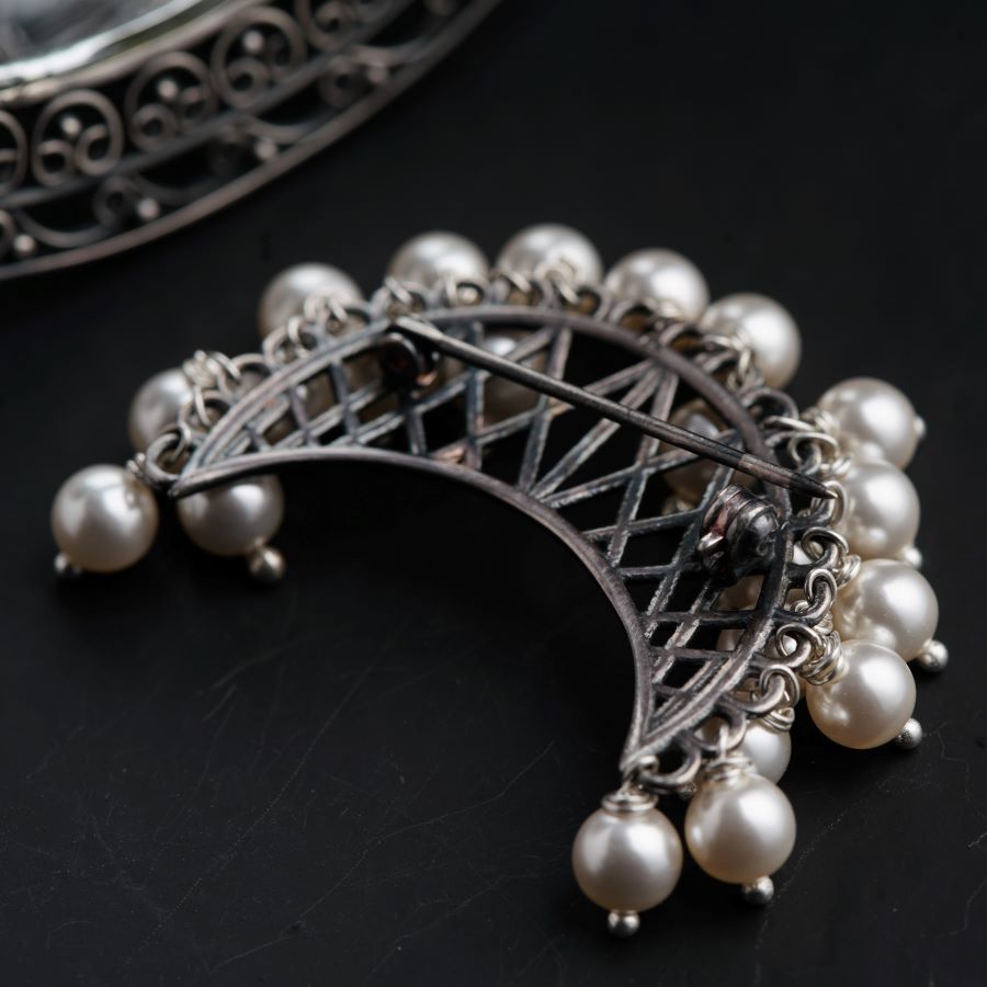 a close up of a brooch with pearls