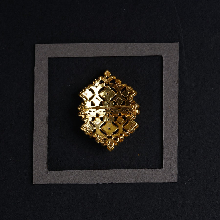a gold brooch sitting on top of a black surface
