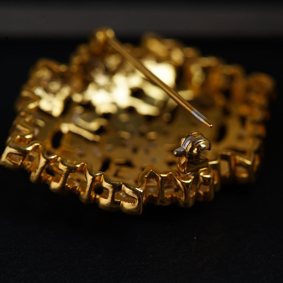 a close up of a gold brooch with a pin in it