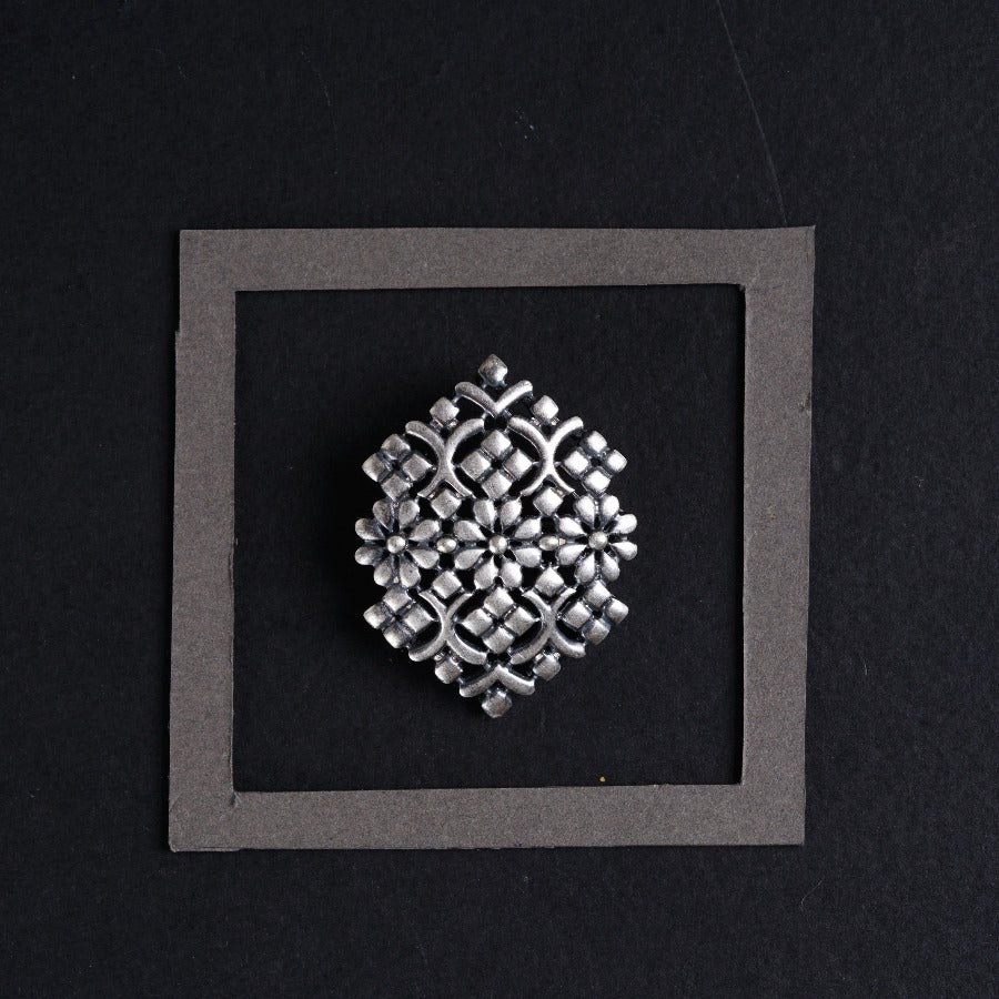 a silver brooch sitting on top of a black surface
