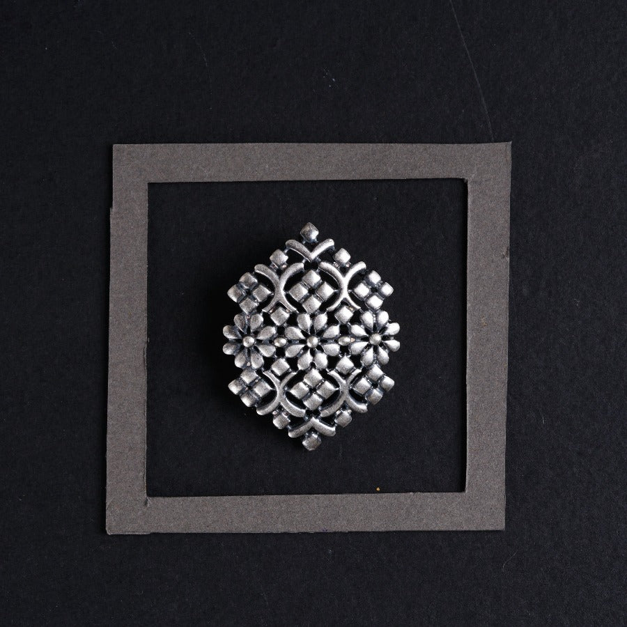 a silver brooch sitting on top of a black surface