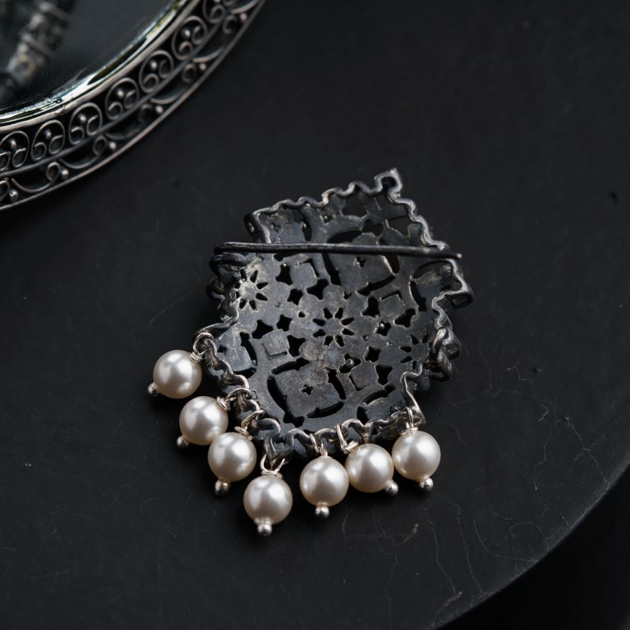 a close up of a brooch with pearls