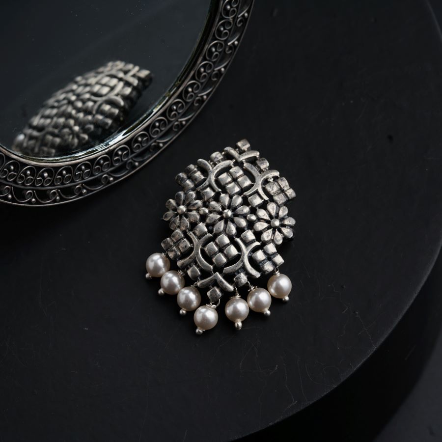 a silver brooch sitting on top of a table next to a mirror